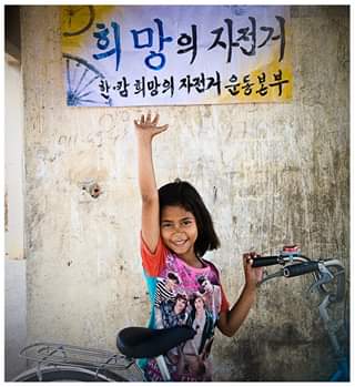 일명 쓰레기마을 '스팅민쩌이'에 사는 소녀 '야임 스라이 니응'(당시 9세)가 자전거를 받고 기뻐하고 있다.
