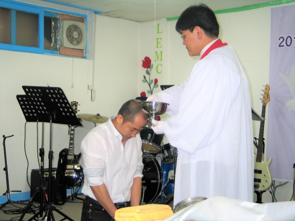 이현성 목사에게 세례를 받고 있는 이주민 성도. 세상의빛선교교회 제공.